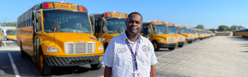 School Bus driver standing in front of a row of buses